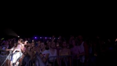 2021-08-06 - Mariupol Şehir Festivali, Ukrayna. Neşeli insanlar telefonları yakalıyor, eller havada, yaz konserleri açık havada. Gece müzik festivalindeki heyecanlı hayranlar, dans etmek, canlı müzik grubu için şarkı söylemek.