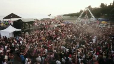 2021-08-08 - Mariupol Şehir Festivali, Ukrayna. Kalabalık ritmik olarak yükseliyor, yüksek enerji karışıklığı, festival atmosferi, açık deniz olayları. Plaj müzik festivalinin havadan görüntüsü, rock hayranları çember çukur oluşturuyor.