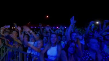 2021-08-07 - Mariupol Şehir Festivali, Ukrayna. Enerjik kalabalık canlı performansı, sahnede renkli ışıkları seviyor. Heyecanlı hayranlar geceleri tezahürat yapıyor, kollar canlı müzik festivali atmosferinde yükseliyor.