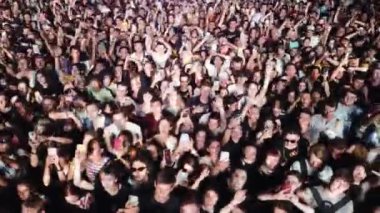 2021-08-06 - Mariupol Şehir Festivali, Ukrayna. Enerjik hayranlar el sallıyor, akıllı telefonları çekiyor, canlı ses, canlı. Gece müzik festivalinde hava aracı sesleri yoğun ve heyecanlı bir kalabalığın üzerine yansıyor..