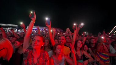 2021-08-08 - Mariupol Şehir Festivali, Ukrayna. Hayranlar konser vermeyi, açık havada anları yakalamayı, el kaldırmayı, şehir gece hayatını seviyorlar. Gece müzik festivali kalabalığı ışıklar açık akıllı telefonlar sallıyor.