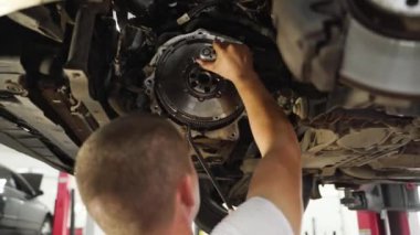 Tamirci araç şanzımanında çalışıyor, vites kutusunu değiştiriyor, debriyaj plakasını ayarlıyor. Otomatik tamirci arabaya debriyaj diski takar. Atölye teknisyeni kaldırılan otomatik altında iletim bileşenlerini düzeltiyor.