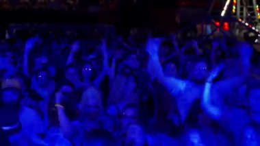 2021-08-07 - Mariupol Şehir Festivali, Ukrayna. Sahne ışıkları partiye katılanların şenlik etkinliğini aydınlatır. Dönme dolap yakınlarındaki açık hava müzik festivalinde enerjik kalabalık dans ediyor..