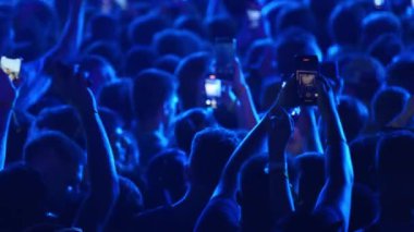 2021-08-06 - Mariupol Şehir Festivali, Ukrayna. Taraftarlar akıllı telefonlarla canlı konser kaydediyor. Heyecanlı müzik festivali kalabalığı geceleri dans ediyor. Aydınlatılmış sahne ve ritmik hareketli enerjik atmosfer.