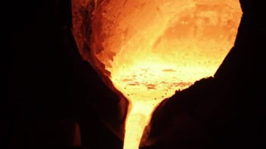 Endüstriyel işçiler dökümhanede eritmeyi denetliyor, dökümhaneye sıvı demir döküyor. Erimiş metal çelik dökme işleminde fırından akar. Metal üretimi aşamaları, ısıya dayanıklı ekipman kullanımı.