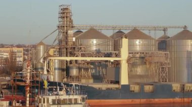 Taşıyıcı sistem, küresel ticaret için gerekli olan tarımsal metalarla dolu. Toplu taşıyıcı gemi yükleme için tahıl ambar terminaline yanaşıyor. Gün doğumunda limana sanayi ihracatı.