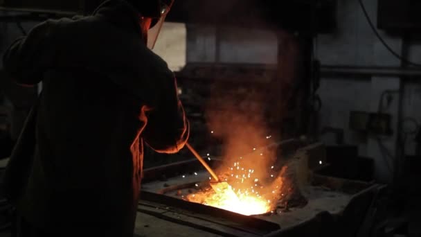 スパークスは 人間が鋼を形作り 工場で製造プロセスをしています 保護ギヤの産業労働者は鋳造物の梯子から金属を溶かします 重工業 金属工業 職場での職人技 — ストック動画