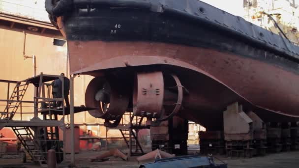 工業造船所での船舶メンテナンス 労働者は溶接 粉砕が付いている乾燥したドックの船を修理します 船体を固定するヘルメットの男性 海洋工学の偉業 船のオーバーホール スチールワークの再構築 — ストック動画