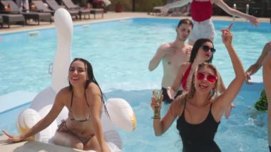 Kadın ve erkek modeller yüzme havuzunda takılıyor, su sıçratıyor, flört ediyor ve poz veriyorlar. Mayolu ve güneş gözlüklü bir grup arkadaş yaz tatillerinde eğlenir ve dinlenir..