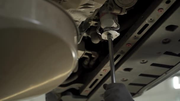 专业汽车服务 日常维修工作 润滑油更换 发动机维修 汽车修理工在车辆上更换机油 熟练地拧开螺丝排泄塞 去除车库里的旧过滤器 — 图库视频影像