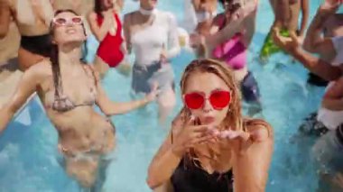 Erkek arkadaşlar ve kız arkadaşlar lüks kulüpteki havuz partisinde yaz havasının tadını çıkarıyorlar. Erkekler ve kadınlar gülümser, el sallar, dalarlar ve turkuaz berrak suda yüzerler. Arkadaşlarla sıcak tatilde gürültülü bir kutlama.