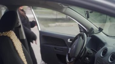Şehir içi iş seyahati, profesyonel yaşam tarzı yakalanmış. Yetişkin iş kadını araca biner, motoru çalıştırır, arabayı hazırlar. Emniyet kemeri takın, aynaları kontrol edin. Kişisel ulaşım, şehir hayatı vurgulandı.