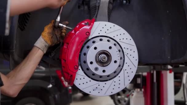 手使用工具安装新的垫 卡尺在轮毂上 汽车修理厂的汽车修理工在汽车上更换制动器盘 供教学 Diy项目使用的车辆维修录像 — 图库视频影像