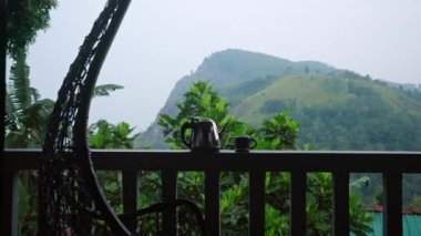 Çaydanlık, lüks terasta çay fincanı, dağ manzarası, çay çiftliği, sakin bir sabah manzarası, sallanan sandalyeli şık bir açık hava rahatlama alanı, refah yolculuğu için mükemmel bir yer. Slomo