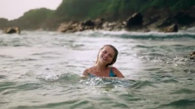 Gülümsemeler, şakacı sıçramalar neşeli sahneler yaratır. Zarif bayan denizde yüzer, mavi elbise dalgalarla harmanlanır. Doğal zemin, güneş ışığı cazibeyi arttırır. Solo gezgin özgürlüğü anı tropikal olarak ele geçirildi. Slomo