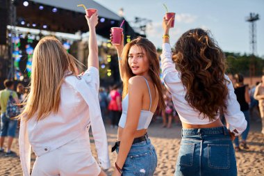 Kızlar renkli içkiler içer, günbatımı konserinde kalabalıkla dans ederler. Bir grup bayan arkadaş kumsalda yaz müzik festivalinin tadını çıkarıyor. Moda kıyafetleri içinde genç kadınlar kutlama yapıyor, dışarıda eğleniyorlar..