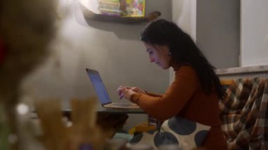 Konforlu kafe masasında dizüstü bilgisayara odaklanmış kadınlar, girişimciler uzaktan çalışıyor, kahveyi yudumluyor, online iş yönetiyor, dijital göçebe yaşam tarzıyla meşgul oluyor, ekranda başarıyla gülümsüyor..