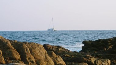 Gezginler deniz yolculuğunun, denizlerdeki maceranın tadını çıkarırlar. Lüks yatlar açık denizde, kayalık sahilden panoramik manzaralı. Boş deniz gezisi, özel tatil. Yelkenli mavi okyanus dalgalarında süzülür.