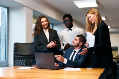 Afrikalı, Arap ve beyaz profesyoneller stratejiyi tartışıyor, dizüstü bilgisayarın başarısını kutluyorlar. Modern ofiste çok ırklı iş adamları işbirliği yapıyor. Kurumsal giyinmiş erkek ve kadınlar takım çalışmasına katılırlar..