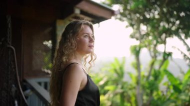 Rahatlamış, dingin dağlık manzarayı, sakin sabahı seviyor. Zarif kadın zengin dağ zeminiyle tatil köyünün balkonunda çayını yudumluyor. Lüks seyahat, huzurlu yaşam tarzı bu huzurlu sahnede birleşti. Yavaşla