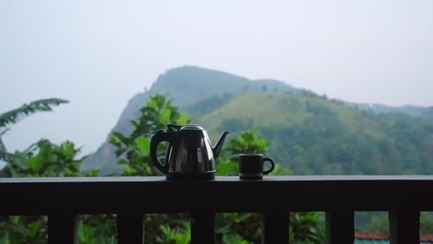 蒸气腾腾的水壶 阳台栏杆上的杯子 相机摇椅 山景秀丽的茶园 清晨沐浴静谧的静谧 完美的奢华生态之旅 — 图库视频影像