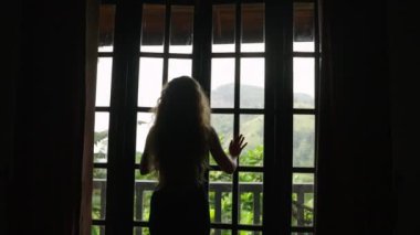 Huzurlu bir sabah, odayı sel basar manzaralı bir gezgin gibi, tropik cennete kaçar. Kadın lüks süitte balkon kapısını açıyor, Sri Lanka 'da Ella Rock manzarası çok güzel. Yavaş çekim.