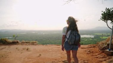 Güçlü esinti saçlarla oynar. Zengin yeşil bitkilere tepeden bakar, aktif yaşlı yaşam tarzını, dağ macerasını somutlaştırır. Sırt çantalı Asyalı yaşlı kadın kayalık Pidurangala Kayası 'nın tepesinde rüzgarlı bir yürüyüş yapıyor..