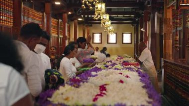 2023-06-01 - Kandy, Sri Lanka. Sri Dalada Maligawa. Dindarlar Budist tapınağının içinde çiçekler sunarlar, bir ayin adağı, geleneksel giyinmiş kadınlar saygılarını sunarlar, süslü püslü kutsal mekanlarda dua ederler..