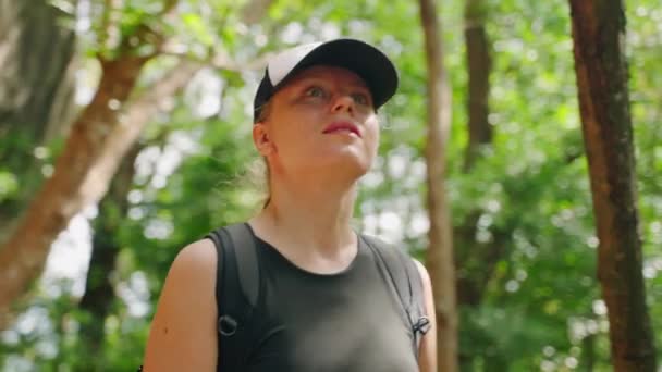 冒险者喝可重复使用的软瓶 享受自然环境中的生态旅行 活跃的女人在富饶的森林里的岩石岩洞中爬行 暂停水化休息 福祉概念 — 图库视频影像