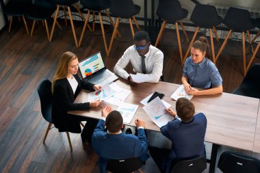 İş kadını dizüstü bilgisayardaki çizelgeyi analiz eder, çalışanlar stratejiyi tartışır. Kadın CEO 'nun başkanlığındaki çok ırklı müzakere masasında. Modern çalışma alanında kurumsal toplantı, çeşitli grup işbirliği.