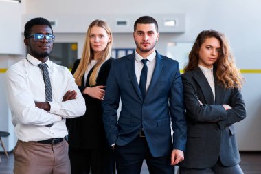 Afrikalı, Kafkas, Arap ve Asyalı meslektaşlar güçlü bir birlik içinde poz veriyorlar. Modern ofiste kendine güvenen farklı iş adamları var. Profesyonel işyerinde melez ırk, cinsiyet eşitliği.