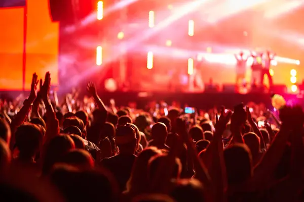 Hayranlar el kaldırıyor, yaz festivalinde müzik dinliyor. Gün batımında açık havada canlı konserde dinleyiciler. Sahne ışıkları heyecanlı kalabalığı aydınlatır. Etkinlik, enerjik enerji ve toplum atmosferiyle tam gaz devam ediyor.