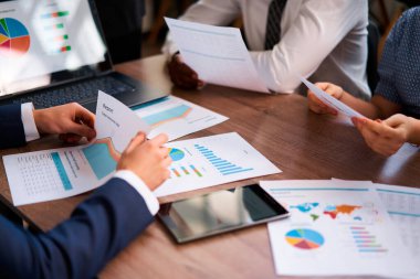 Kurumsal grup işbirliği yapar, görüşleri paylaşır, veriye dayalı çözümlere odaklanır. Çok ırklı ekip iş yerindeki iş ölçümlerini analiz ediyor, raporlar üzerindeki renkli grafikleri tartışıyor, strateji planlıyor.