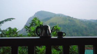 Çay deneyimi, lüks yazlık evde manzaralı doğa, sakin çiftlik manzarası. Dolly shot çaydanlık, bardak trabzanda... dağ manzaralı, Ella Rock, Sri Lanka arka planda..