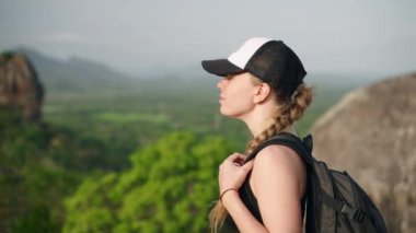 Sırt çantalı turist, antik Sri Lanka kalesine bakıyor. Macera arayan kadın, zengin ormanda Sigirya Kayası 'nın arka planında yürüyüş yapıyor. Solo gezgin dingin doğa ve açık hava yolculuğunun tadını çıkarır. Yavaşla