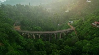 Ormanla çevrili tek başına gezen bir turist. Gündoğumu, Sri Lanka 'daki Dokuz Kemer Köprüsü' nü aydınlatıyor. Simgesel seyahat simgesi. Erken sabah taş yapısı, tarihi mimari, doğal güzellik..