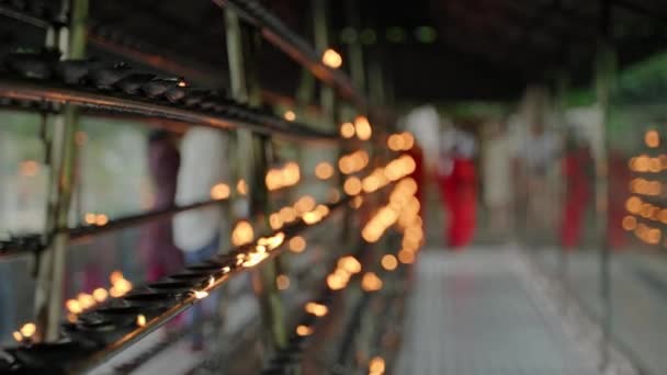 Rows Flickering Flames Line Racks Blurred Figures Moving Serene Religious — Vídeos de Stock