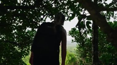 Sırt çantalı maceraperest kadın yürüyüşçü Sigiriya Kayası 'na hayran kaldı. Siluet yaprakları, manzaralı bir manzara sabahı, tarihi bir yere bakıyor. Yalnız gezgin eko-turizm doğa güzelliği.