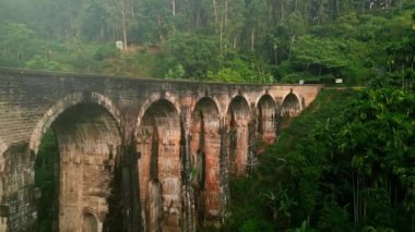 Hava aracı görüntüsü ikonik görkemli kemerler ve tropikal orman. Gündoğumu Dokuz Kemer Köprüsü 'nü yıkıyor, Sri Lanka ormanının ortasında tarihi viyadük. Sabahın erken saatlerinde ünlü demiryolu simgesinde dinginlik.