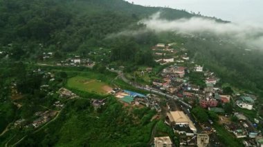 Sri Lanka kasabası yakınlarında sis, tepeleri demiryolu raylarıyla kaplıyor. Drone Haputale yemyeşil çay bahçelerinden yılan gibi geçen treni yakalıyor. Gezginlerin manzarası, serin dağlarda manzaralı bir yolculuk..