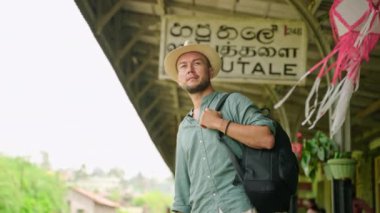 Kameralı adam otantik Sri Lankalı taşıma merkezini araştırıyor. Sırt çantalı Asyalı turist Haputale tren istasyonunda. Zengin dağlarda tren yolculuğuna hazır şapkalı bir gezgin. Yavaşla