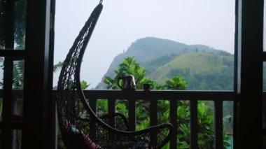 Kamera buharlaşan çaydanlık ve fincana doğru süzülüyor lüks teras korkuluklarında, pofuduk sallanan sandalyeler, dağ manzaraları ve sakin bir sabah esansını yakalayan zengin çay bahçeleri. Yavaşla