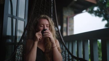 Huzurlu, ılık bira içmeyi, rahat bir verandada sakin bir atmosferi ve zengin manzarayı seviyor. Kadın salıncakta sallanıyor, manzaralı terasta sıcak çayını yudumluyor, şafak vakti çay bahçelerinde..