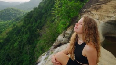 Dişi, sakin manzaradan, doğada meditasyon anından zevk alır. Kadın ormandaki şelalenin tepesinde uçurumun kenarında oturuyor. Huzur içinde nefes al, bilinçli seyehat et. Yalnız gezgin vahşi doğayı keşfeder, huzuru bulur..