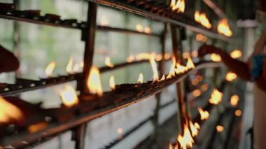 Metal tribünlerde alevler yanıp sönüyor, umut, bağlılık. Budist tapınağında ruhani ayinler için gaz lambaları yakıyor. Kutsal yerde ibadet ritüeli, dingin ortam, Asya 'da dini uygulama..