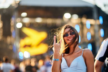 Seyirciler, konser, eğlence, gençlik, dans havası. Gülümseyen genç kadın yaz müzik festivalinden, plaj sahnesinden, barış tabelasından, güneşli saçlardan, günlük modadan, hareketli gece hayatından hoşlanıyor..