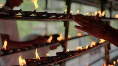 Geleneksel alevler kutsal mekanı aydınlatır, kadınlar dini ayinler yapar, dua eder, barış için meditasyon yapar. Kandy, Sri Lanka 'daki Budist tapınağında petrol lambaları dindarları.