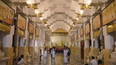 2023-06-01 - Kandy, Sri Lanka. Geleneksel mimari, kutsal mekanda dini sanat. Ziyaretçiler Uluslararası Budist Müzesi 'ni geziyor, altın Buda heykellerinin yanından geçiyor, ayrıntılı duvar resimleri çiziyor..