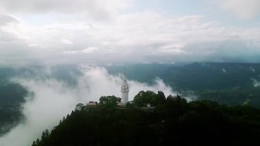 Bulutlar, mistik bir ortam yaratarak dönüm noktasını kaplar. Sri Lanka 'daki sisli dağların ortasındaki Ambuluwawa Kulesi' nin dronu. Hava manzaralı bitkiler, tepenin üstünde eşsiz mimari, popüler seyahat merkezleri..