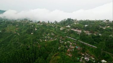 Zengin çay bahçeleri olan Haputale dağları. Tren sisli Sri Lanka dağlarında seyahat eder. Seylan 'da demiryolu turizmi. Asya kırsalında manzaralı bir yolculuk. Hareket halindeki trenin yüksek dron görüntüsü.